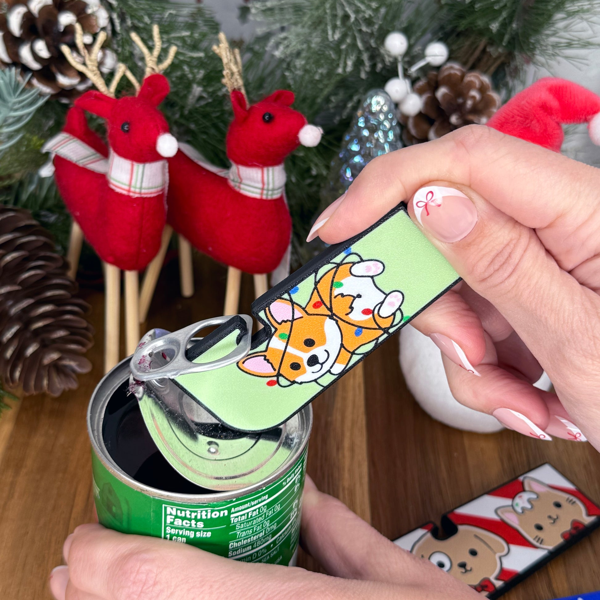 Hand using a Tab Buddy XL with a cartoon corgi design in front of Christmas decorations