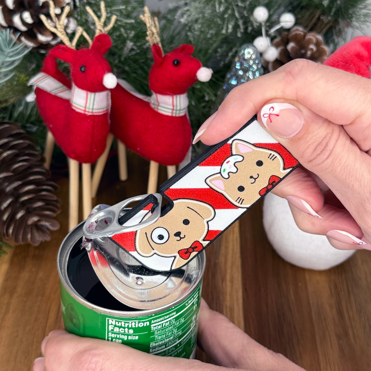 Hand using a Tab Buddy XL with cartoon gingerbread cat and dog design in front of Christmas decorations