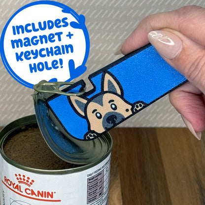 A German Shepherd-inspired Tab Buddy XL is used to peel back the lid of a can of dog food. Descriptive text reads "Includes Magnet + Keychain Hole!"