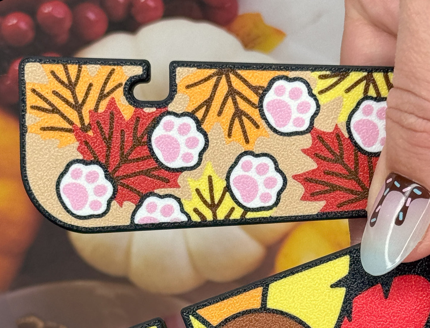 Tab Buddy XL with floral and leaf pattern with paws held by a hand