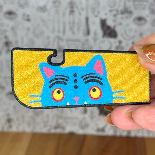 Colorful cat-designed Tab Buddy XL held by a hand against a gray background