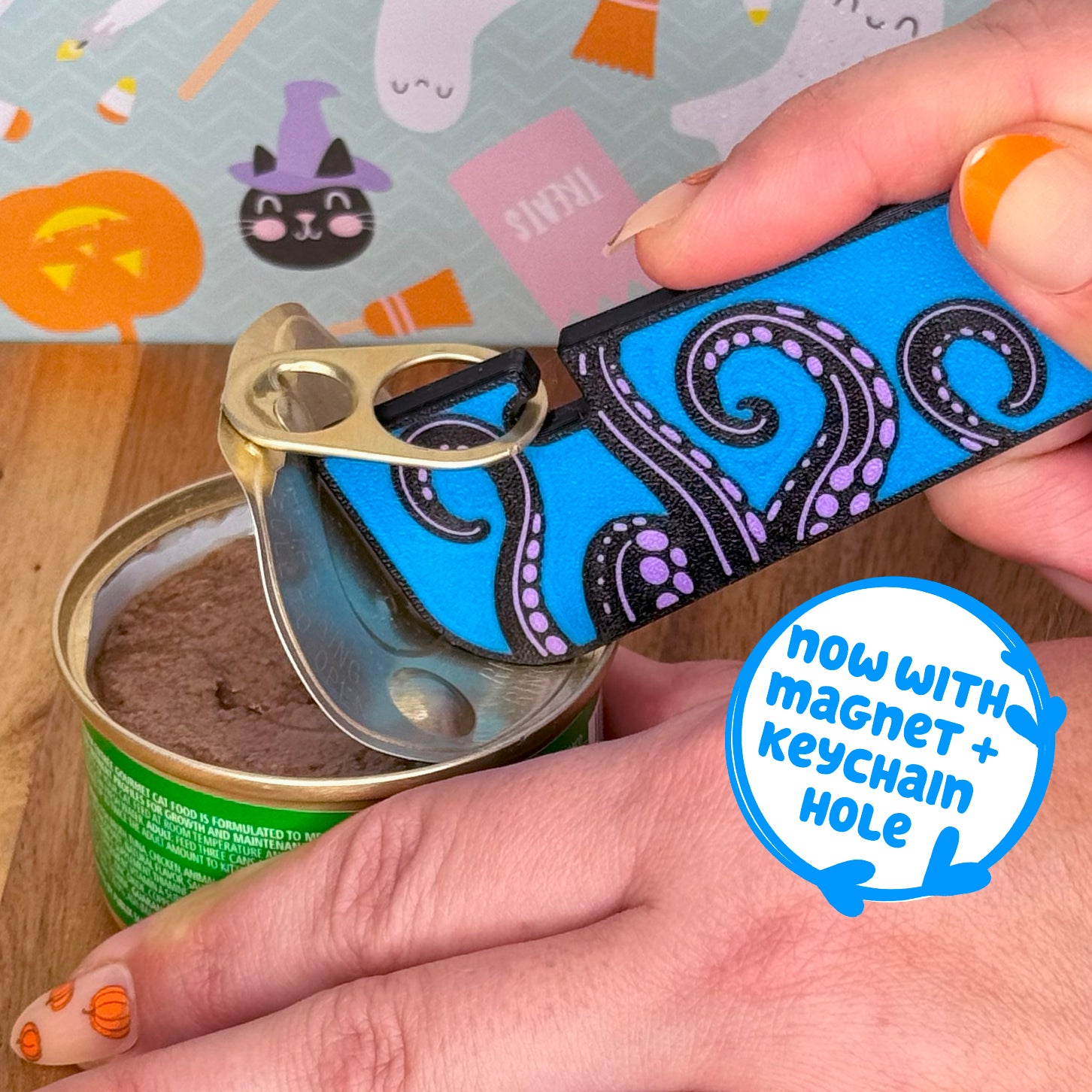 Person using a Tab Buddy XL with a blue and black tentacle design on a can, with a Halloween-themed background with text that reads 'now with magnet + keychain hole'