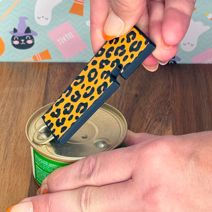 Person using an orange leopard print Tab Buddy XL to lift the tab on a can.
