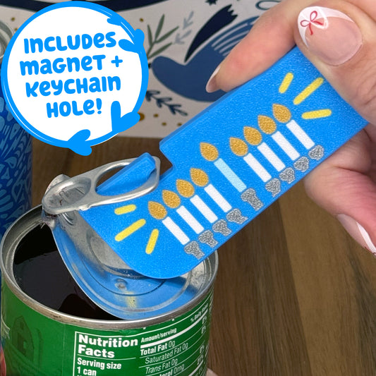 Hanukkah menorah design Tab Buddy XL is used to open a can of vegetables. Text notes the Tab Buddy XL includes a magnet and keychain hole.