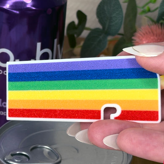 Rainbow striped Tab Buddy XL with a held by a hand, blurred background
