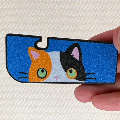 Tab Buddy XL with a calico cat design held by a hand on a textured beige background
