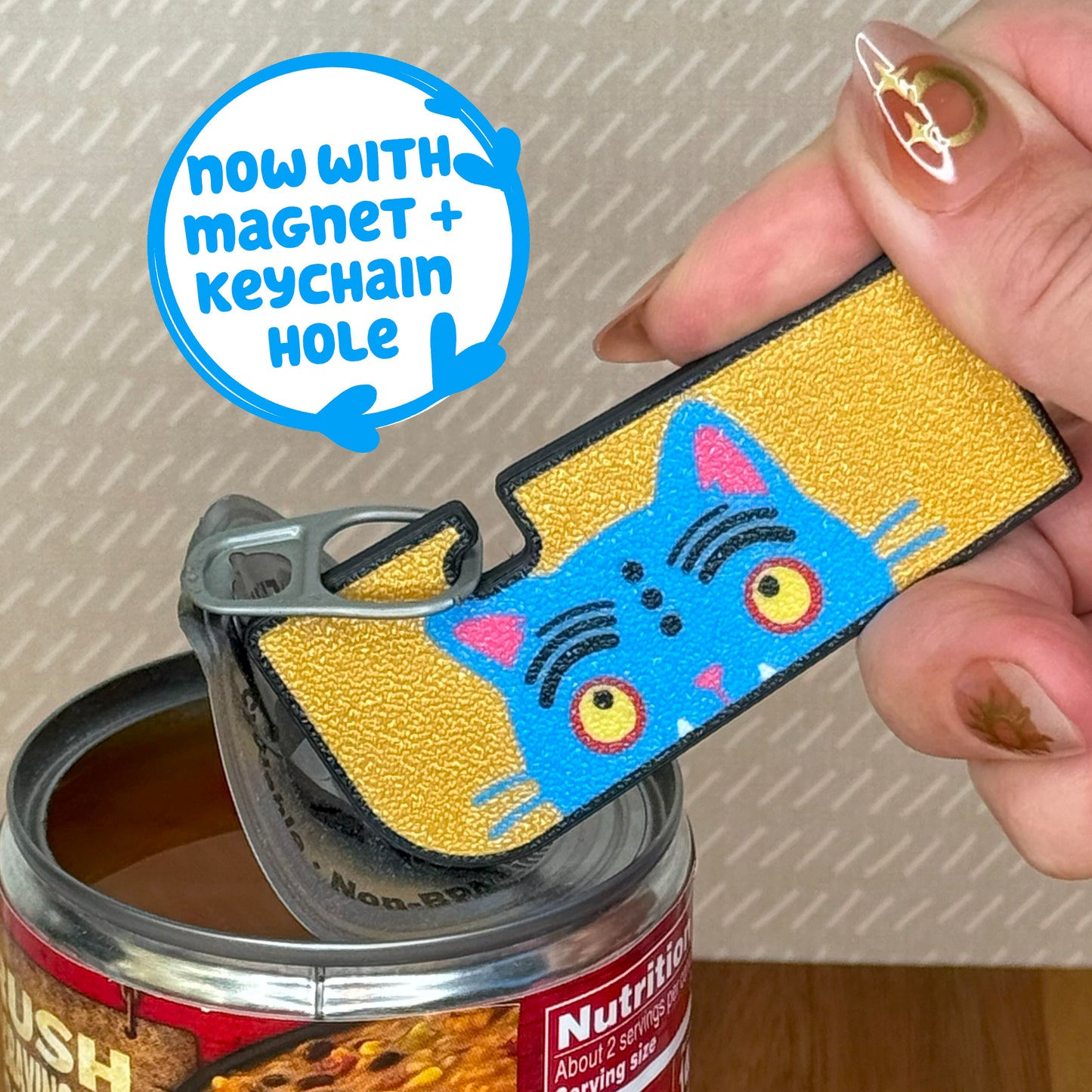 Cat-themed Tab Buddy can opener with magnet and keychain hole feature, held over a can.