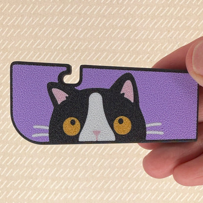 Tab Buddy XL with a Tuxedo Cat design held by a hand on a beige background