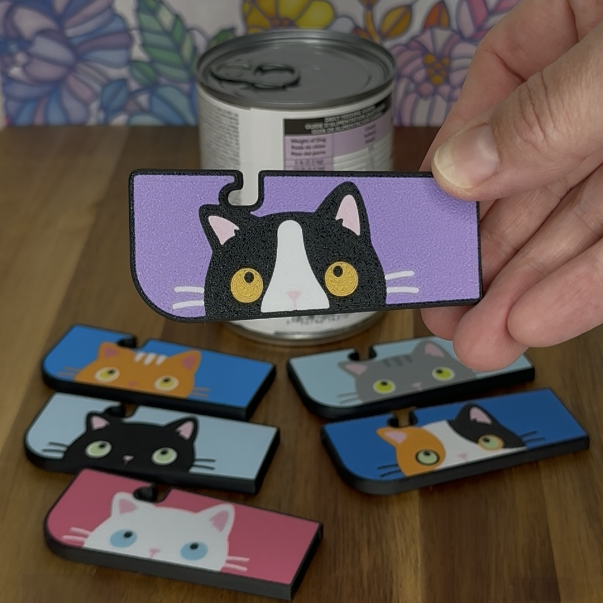 Hand holding a Tab Buddy XL with a Tuxedo Cat design a wooden surface.