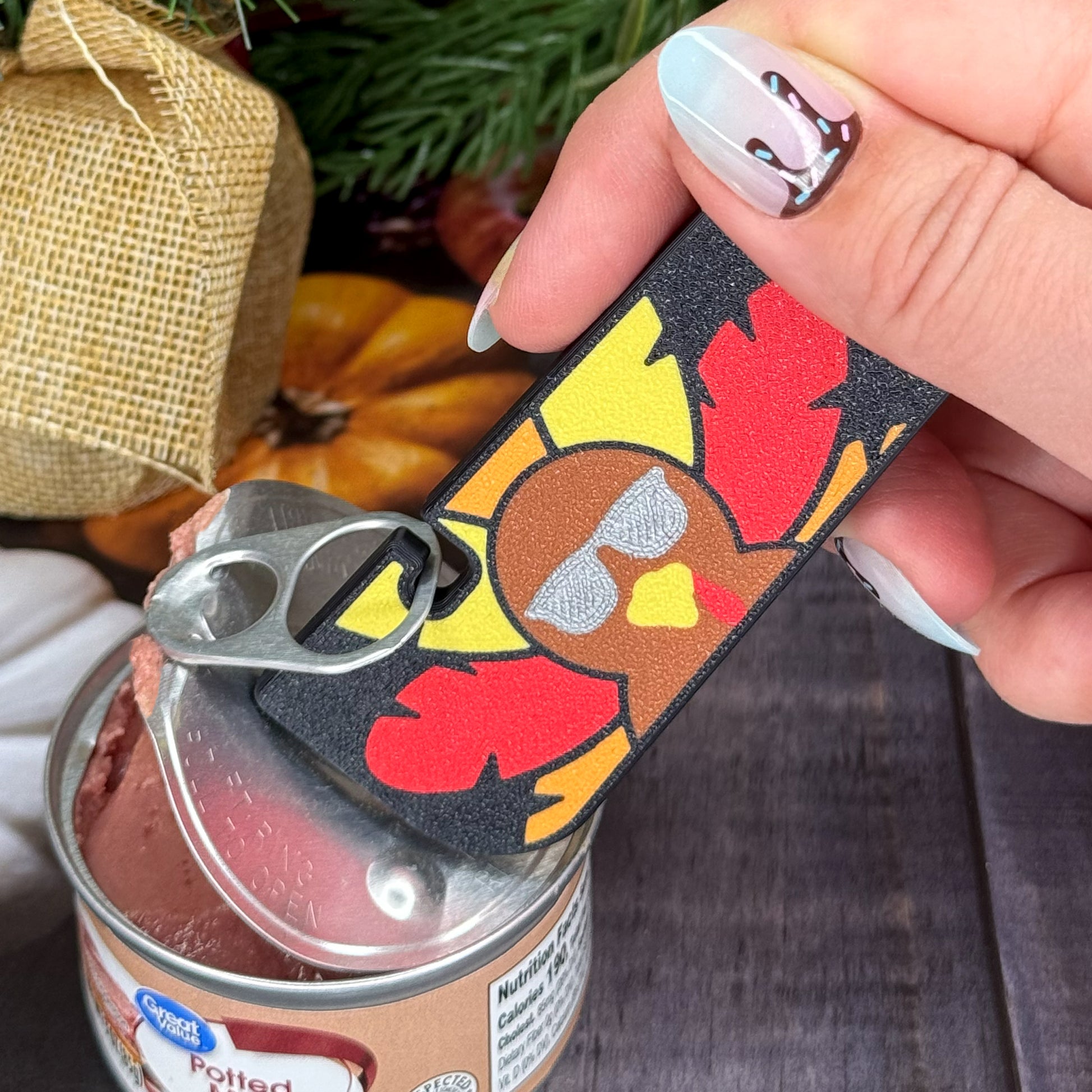 Hand holding a Tab Buddy XL with a colorful turkey design, used to open a can.