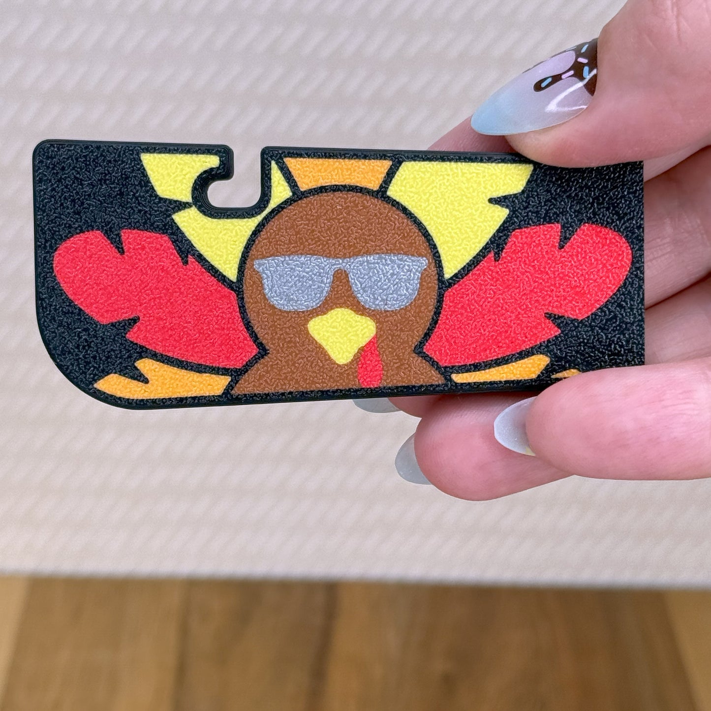 Turkey-shaped Tab Buddy XL with sunglasses held by a hand on a neutral background