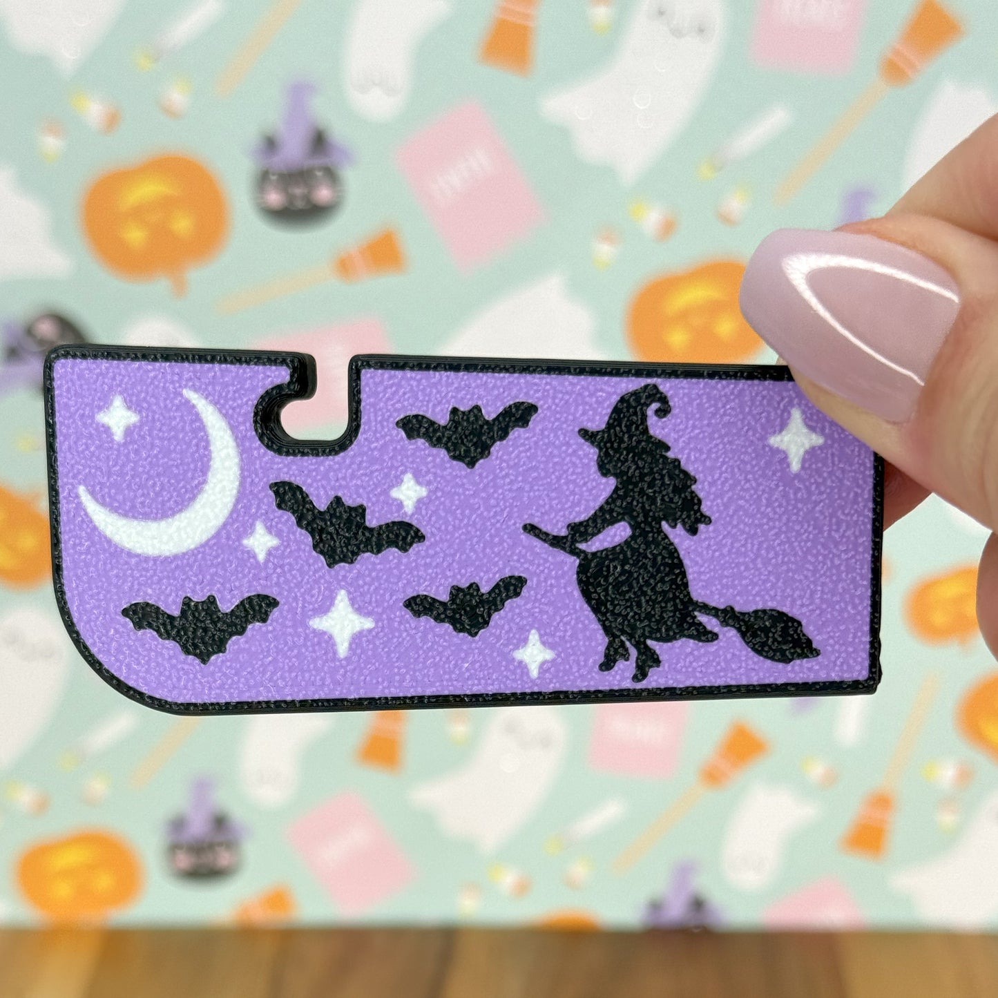 Halloween-themed Tab Buddy XL with a witch and bats on a purple background, held by a hand.