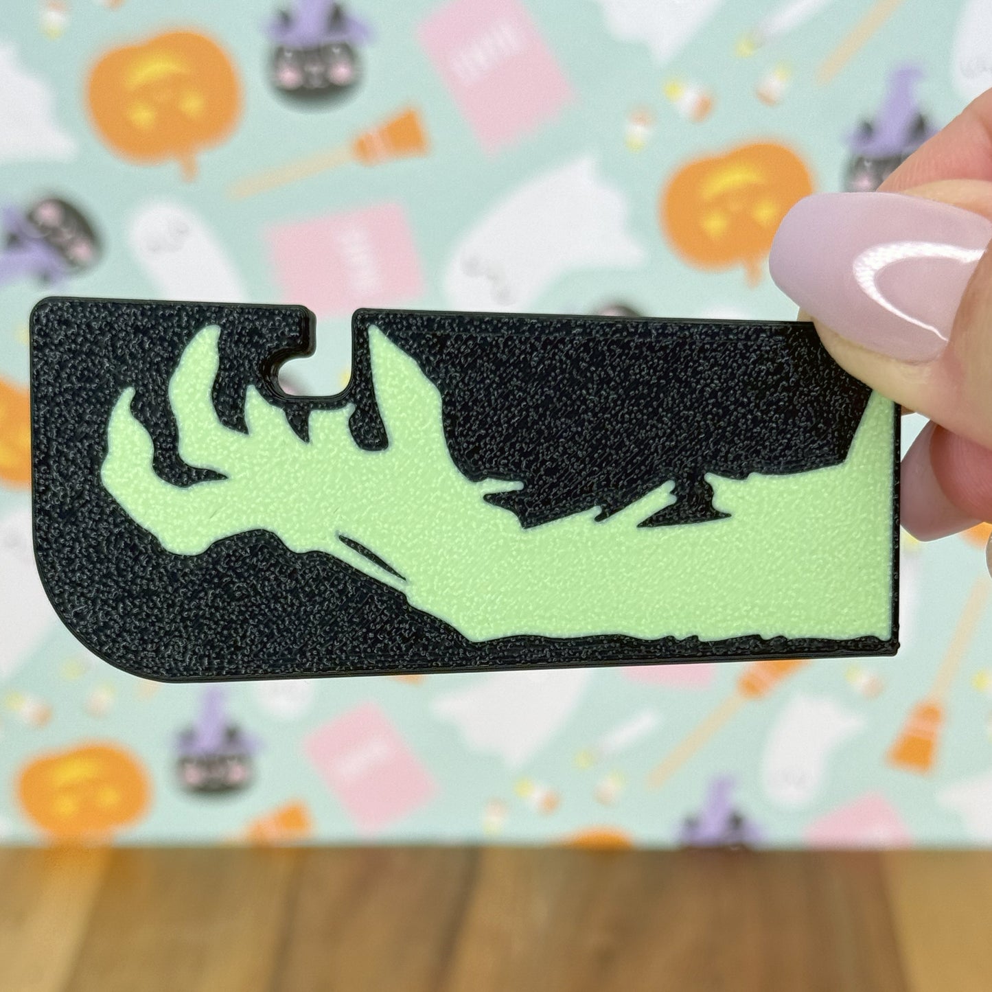 Black and green Tab Buddy XL with hand design held by a hand on a colorful background